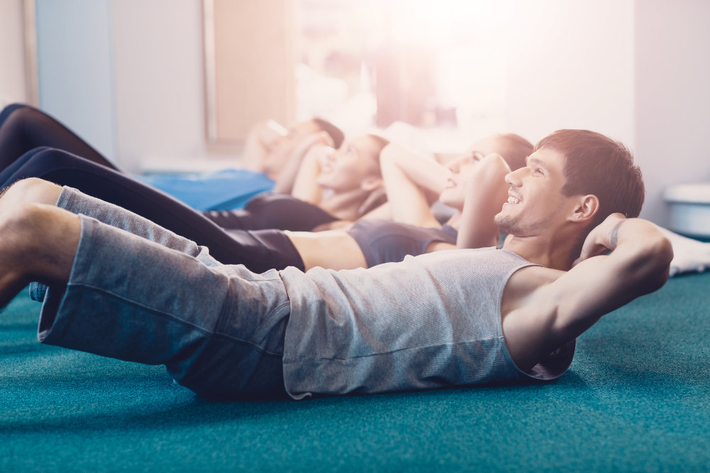Happy people doing an exercise on a crunches lying